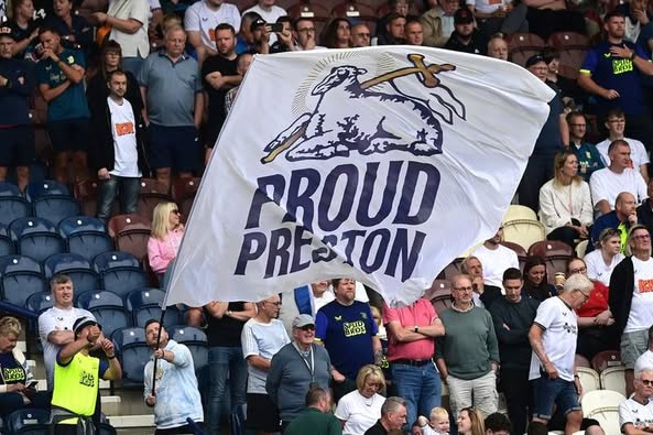 Large Proud Preston flag in front of supporters in a stand.