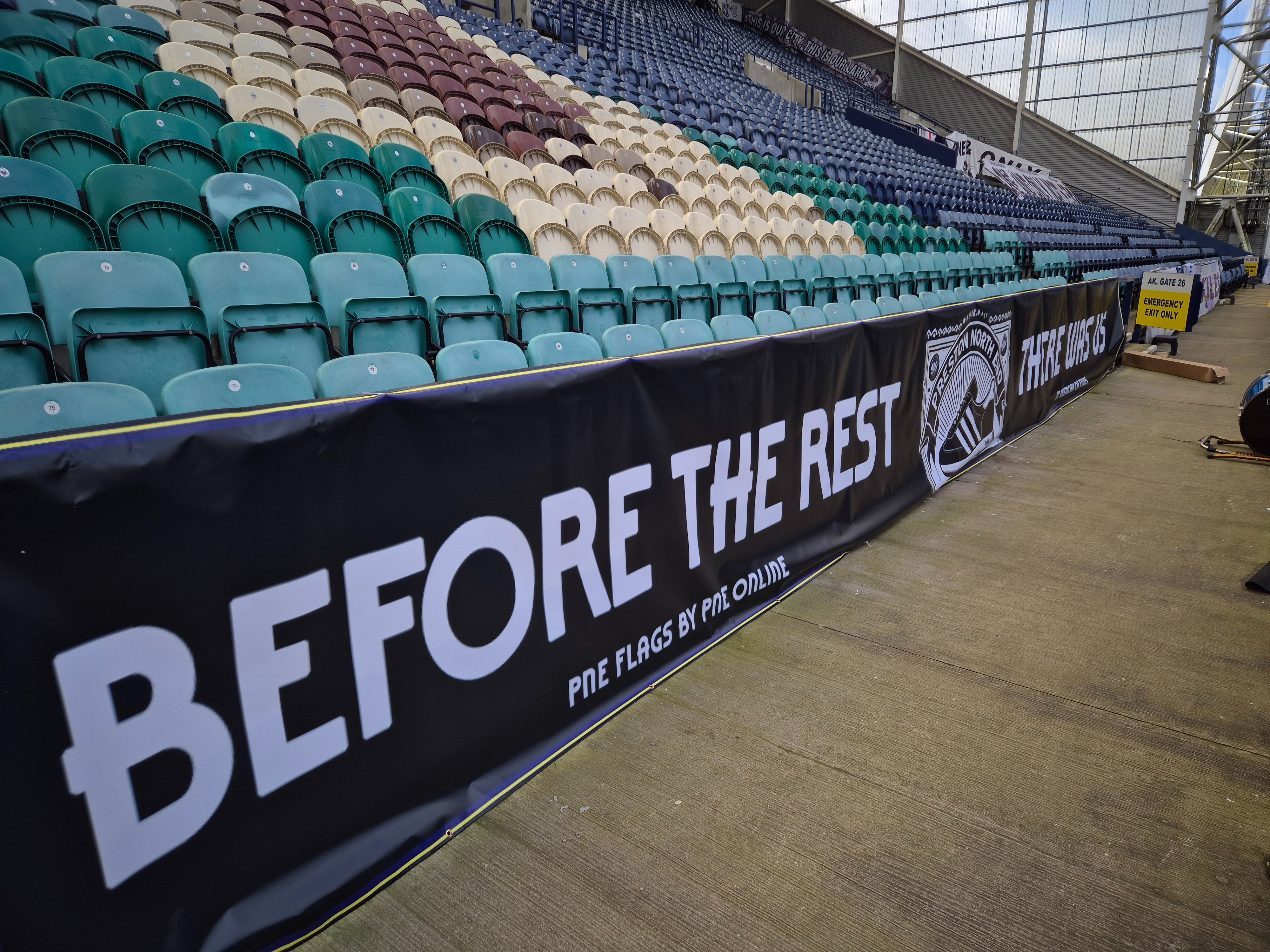 Long PNE Flags banner installed along the front of a stand at Deepdale.
